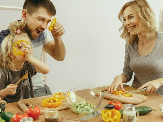 cute-little-girl-her-beautiful-parents-are-cutting-vegetables-smiling-while-making-salad