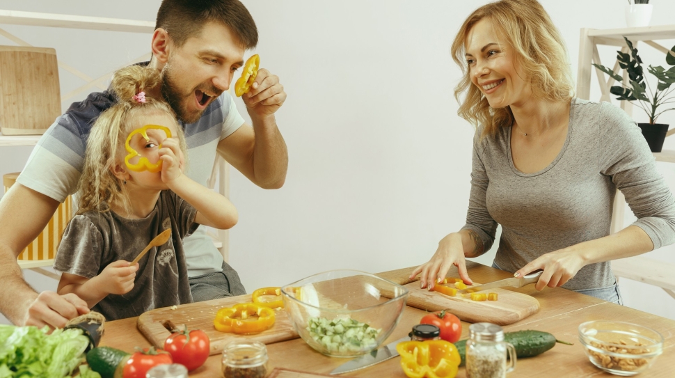 cute-little-girl-her-beautiful-parents-are-cutting-vegetables-smiling-while-making-salad